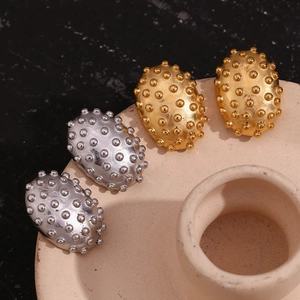 Macro shot of gold and silver textured oval stud earrings with dome-shaped beads