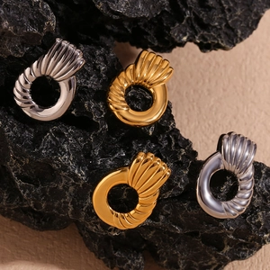 Macro shot of 18K gold and silver plated twisted hoop earrings on black stone texture