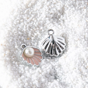 Pink enamel shell pendant with white pearl and silver metal shell charm on sand