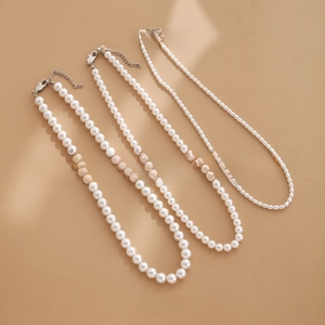 Three rows of cream white pearl necklaces in various sizes with silver lobster clasps