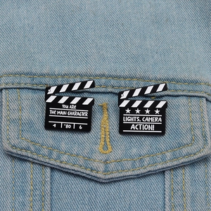 Enamel movie clapperboard brooches on denim jacket with inspirational quotes
