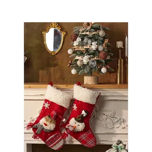 Set of two red felt Christmas stockings with snowman design hanging on a white fireplace
