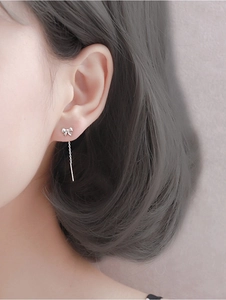 Macro view of S999 sterling silver bow tassel earrings on model showing detail