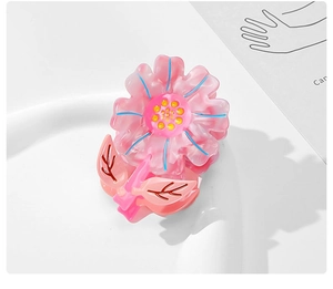 Detail showing pink acetate flower hair claw with blue outlines on a white ceramic tray