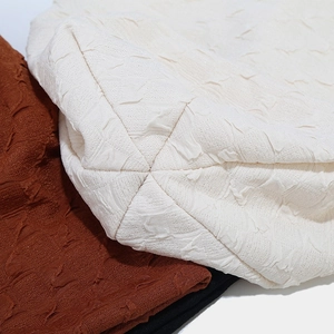 Detail of popcorn textured fabric on slouchy beanies in cream, brown, and black colors