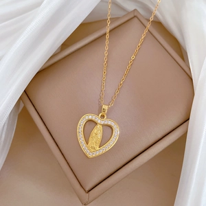 Elegant gold heart pendant necklace with relief portrait on a beige jewelry box