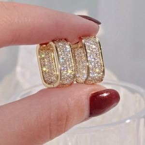 Macro shot of gold plated square hoop earrings with shimmering pave set zircon stones