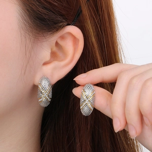 Close-up of two-tone oval earrings with textured metallic surface and gold cross lines
