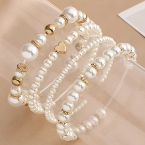 Multilayer white pearl bracelet set with golden beads and a heart charm on glass