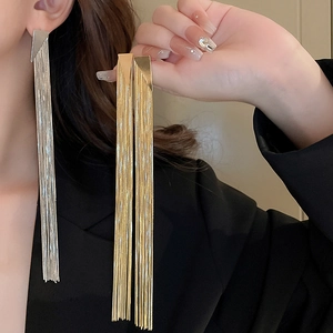 Detail of long metal tassel earrings with geometric triangle studs in gold and silver