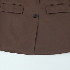 Detailed view of the dark brown blazer waist featuring flap pockets and a single button