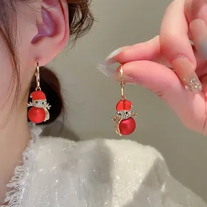 Detailed view of red enamel Christmas earrings with diamond accents on a model