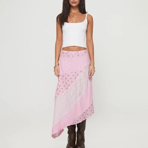 Détail d'une jupe longue à pois rose avec un design superposé et des motifs floraux