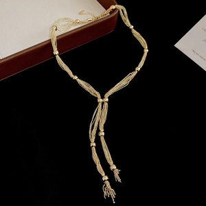 Detail of layered gold beaded Y-necklace with elegant tassels in a jewelry box