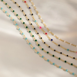 Detail of colorful beads on five gold chains in turquoise, green, black and mixed colors