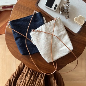 Close-up of minimalist navy and cream canvas crossbody bags with brown leather straps