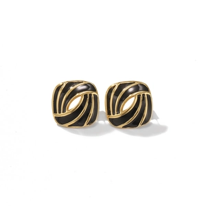 Macro shot of French vintage square gold-plated earrings with black enamel swirl texture