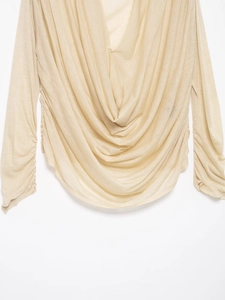 Detail of light beige long sleeve top featuring a draped V-neckline and ruched texture