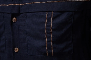 Detail of navy blue shirt pocket with double stitching and amber textured buttons