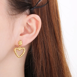 Detail showing the textured 18k gold heart-shaped stud earring on a female model