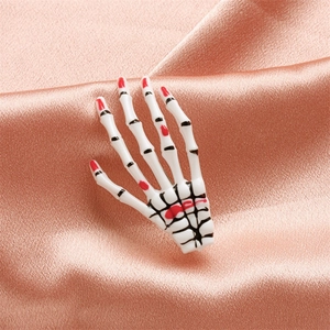 Macro shot of white skeleton hand clip with red nail tips on pink satin fabric