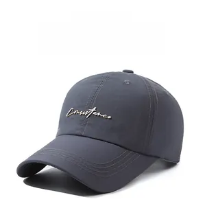 Detail of dark grey baseball cap featuring a gold metal Consistence script logo and stitching