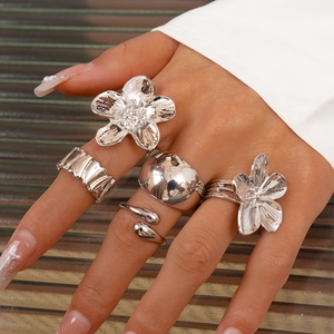Close-up of five-piece silver irregular flower rings set worn on female hand