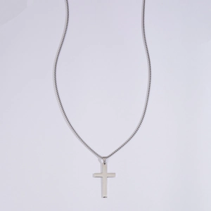 Macro view of a minimalist silver cross pendant made of polished stainless steel metal