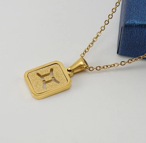 Detail showing a golden square Gemini pendant with sandblasted finish and polished borders