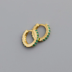 Macro shot of gold S925 sterling silver hoop earrings with inlaid green cubic zirconia