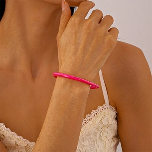 Gros plan d'un bracelet en acrylique rose pêche porté au poignet avec dentelle élégante