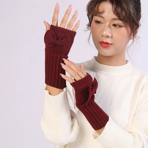 Detail of wine red knitted fingerless gloves featuring a decorative bow on the wrist