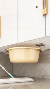 Detail of silver stainless steel hook holding a basin under a white cabinet