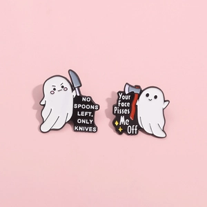 Detail of two white cartoon ghost enamel pins with funny captions on a pink background