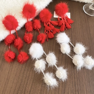 Detail of winter earrings with red and white fur balls, tassels, and resin flowers