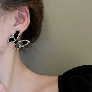 Close-up of a silver butterfly earring with black inlay worn by a female model
