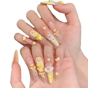 Handmade stiletto press-on nails featuring 3D yellow bear, lace bow, and cream castle art