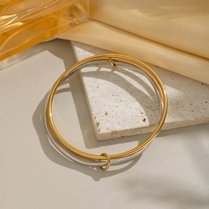 Detail shot of interlaced gold and silver geometric rings on a stone surface