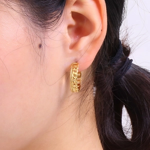 Nahaufnahme eines vergoldeten 18K Edelstahl-Kettenohrrings, getragen von einem Modell