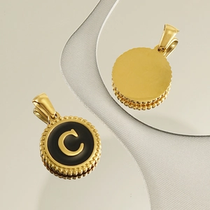 Detail of 18K gold letter C pendant with black enamel finish and beaded edges on silk