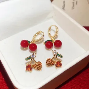 Gold cherry stud earrings with red beads and sparkling zircon stones in a jewelry box
