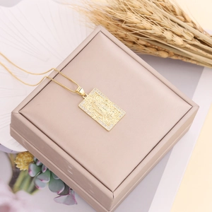 Close-up of gold Virgin Mary pendant with cubic zirconia on a beige jewelry box