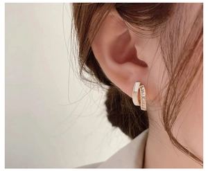 Nahaufnahme eleganter zweilagiger Goldohrstecker mit weißem Inlay und glitzernden Zirkonia