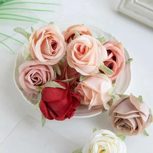Assorted artificial silk rose heads in pink, red, and white on a decorative white plate