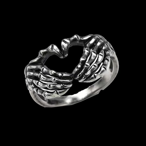 Macro shot of gothic heart ring shaped by skeleton hands with vintage silver finish
