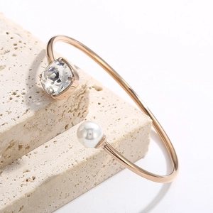 Dettaglio del bracciale a C in oro rosa con cristallo quadrato e perla su pietra bianca