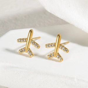 Macro shot of gold airplane stud earrings with sparkling white zirconia on a white stand