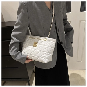 Detailed view of white quilted shoulder bag with gold chain strap and metal lock