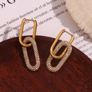 Detail of 18K gold-plated double-loop earrings with zircons on dark wooden stand