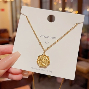 Macro shot of gold stainless steel necklace with irregular floral embossed pendant detail